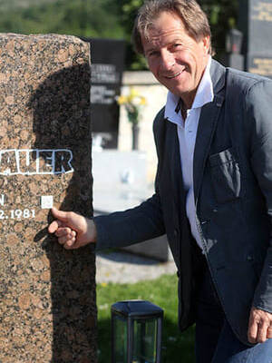 Johannes Bauer der Gründer von Andenken Bewahren steht vor einem Grab mit QR Code
